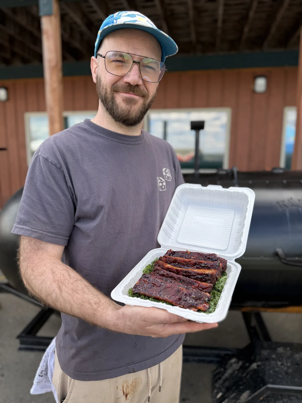 Saucy Rossy holding a fresh box of smoked ribs